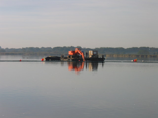 Small hydraulic dredge working inside a floating turbidity curtain on a broad lake