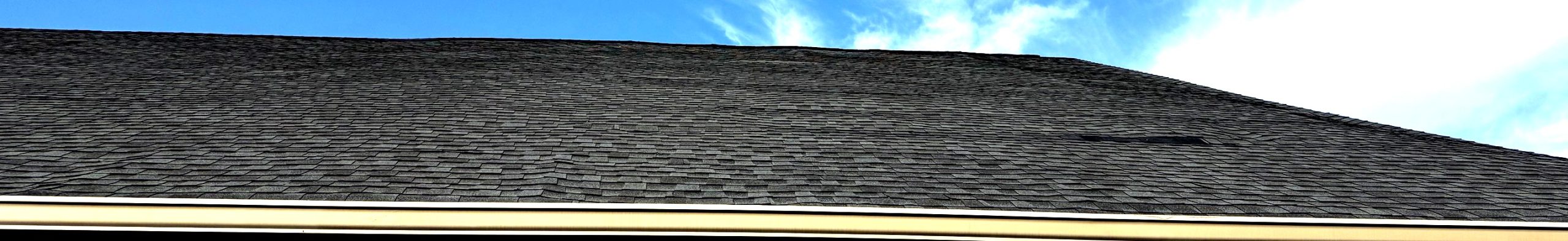 Contrast-enhanced close-up of shingle roof showing alternating light and dark bands over unsupported sheathing edges.